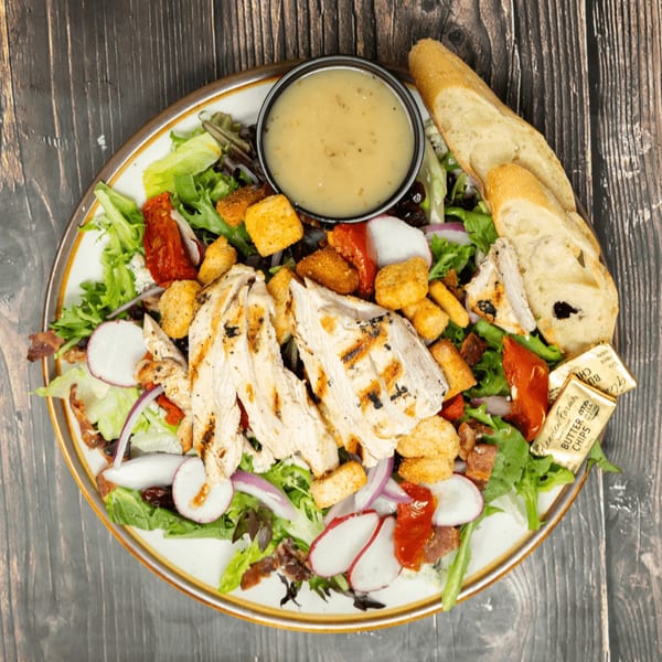 Grilled chicken salad with croutons, radishes, red onion, sun-dried tomatoes, and dressing.