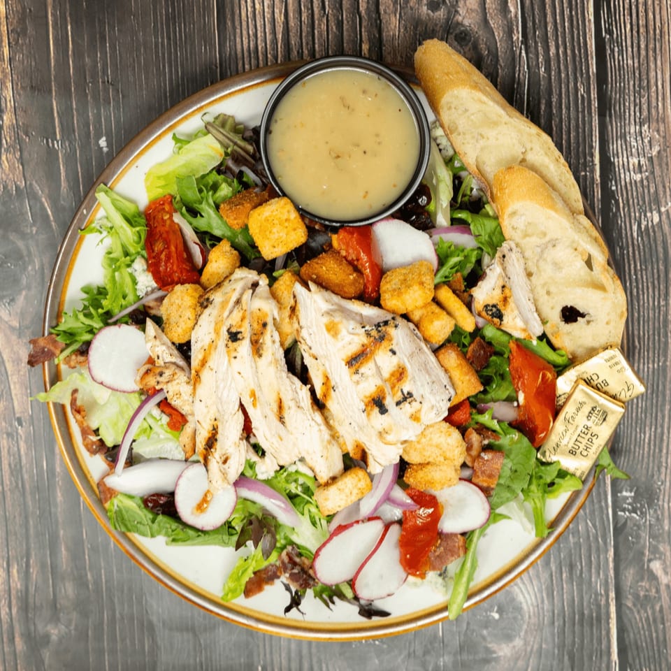 Grilled chicken salad with croutons, radishes, red onion, sun-dried tomatoes, and dressing.