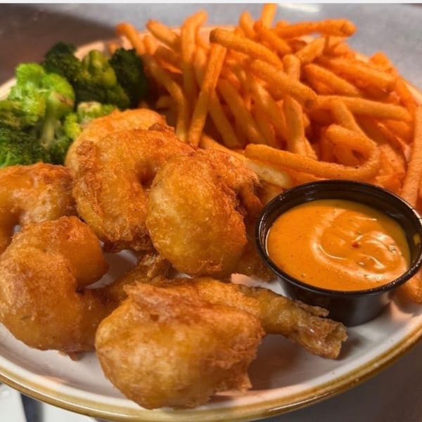 Plate of golden fried shrimp, crispy french fries, steamed broccoli, and a side of dipping sauce.