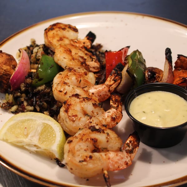 Grilled shrimp skewers with bell peppers, onions, mushrooms, wild rice, lemon, and dipping sauce.